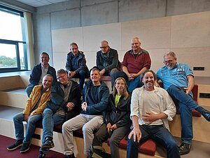 Gruppenbild mit Alumni in zwei Reihen sitzend im Learning Center der Bibliothek an der DHBW Mannheim. 