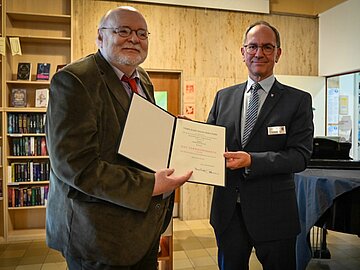 Porträt von Herr Le Blanc, wie er in der Phantastischen Bibliothek die Urkunde von Hr. Ullrich überreicht bekommt. 