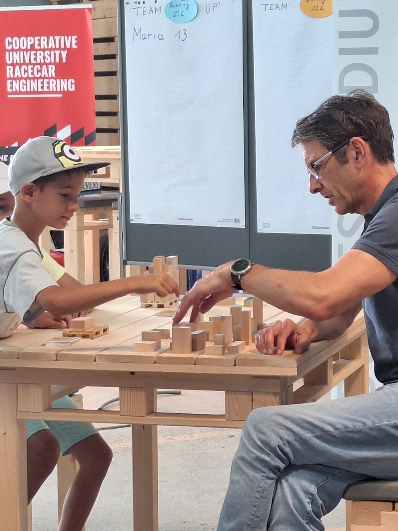 21.06.2023: Prof. Harald Hartmann beim Logistik-Spiel mit einem jungen Besucher am DHBW-Stand