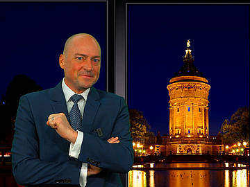 DHBW-Professor Prof. Michael Schröder im Late-Night-Studio - im Hintergrund der angestrahlte Mannheimer Wasserturm bei Nacht