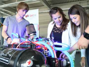 3 Studierende betrachten einen Wasserstofftank an einem Elektromotor im Motorenlabor der DHBW Mannheim.