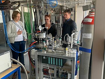 Ein Wissenschaftler der DHBW Mannheim erklärt zwei Damen, wie der elektrochemische Verdichter funktioniert.