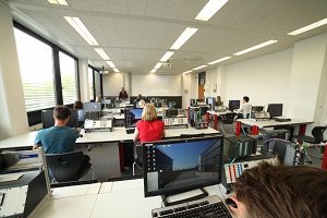 Raum mit PCs, an dem Studierende sitzen und Komponenten programmieren, um Maschinen zu steuern