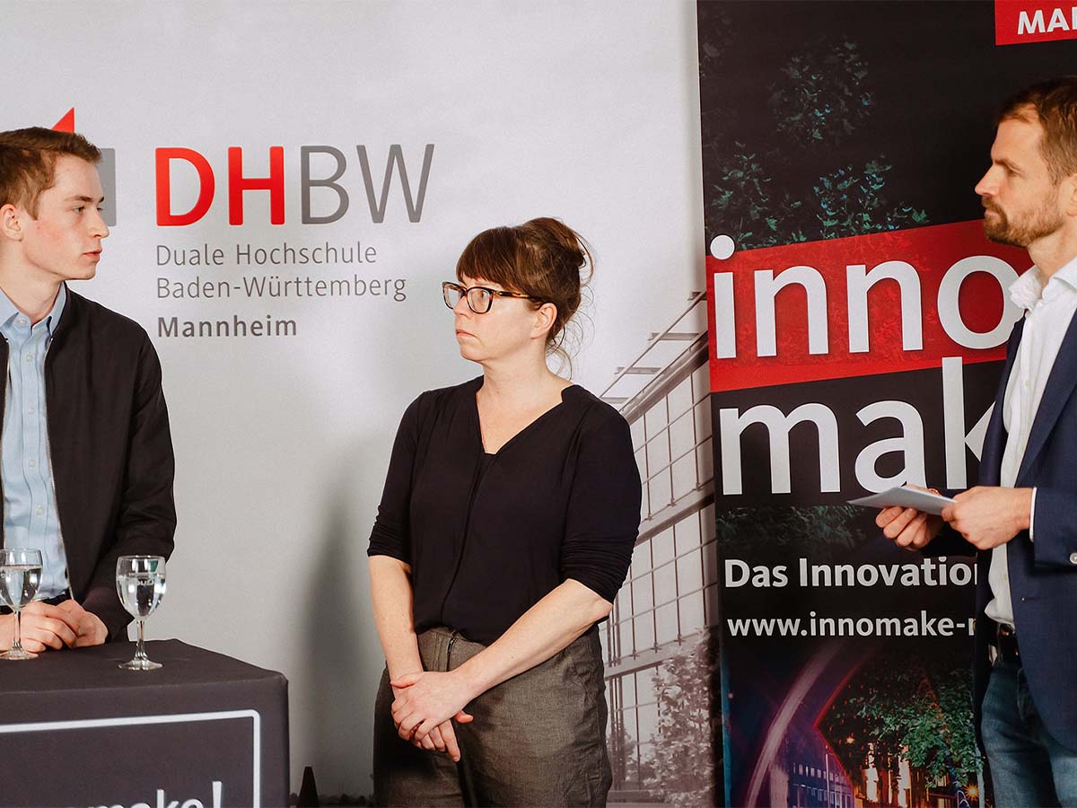 3 Personen vor den Roll-ups der DHBW-Mannheim und des innomake Festivals
